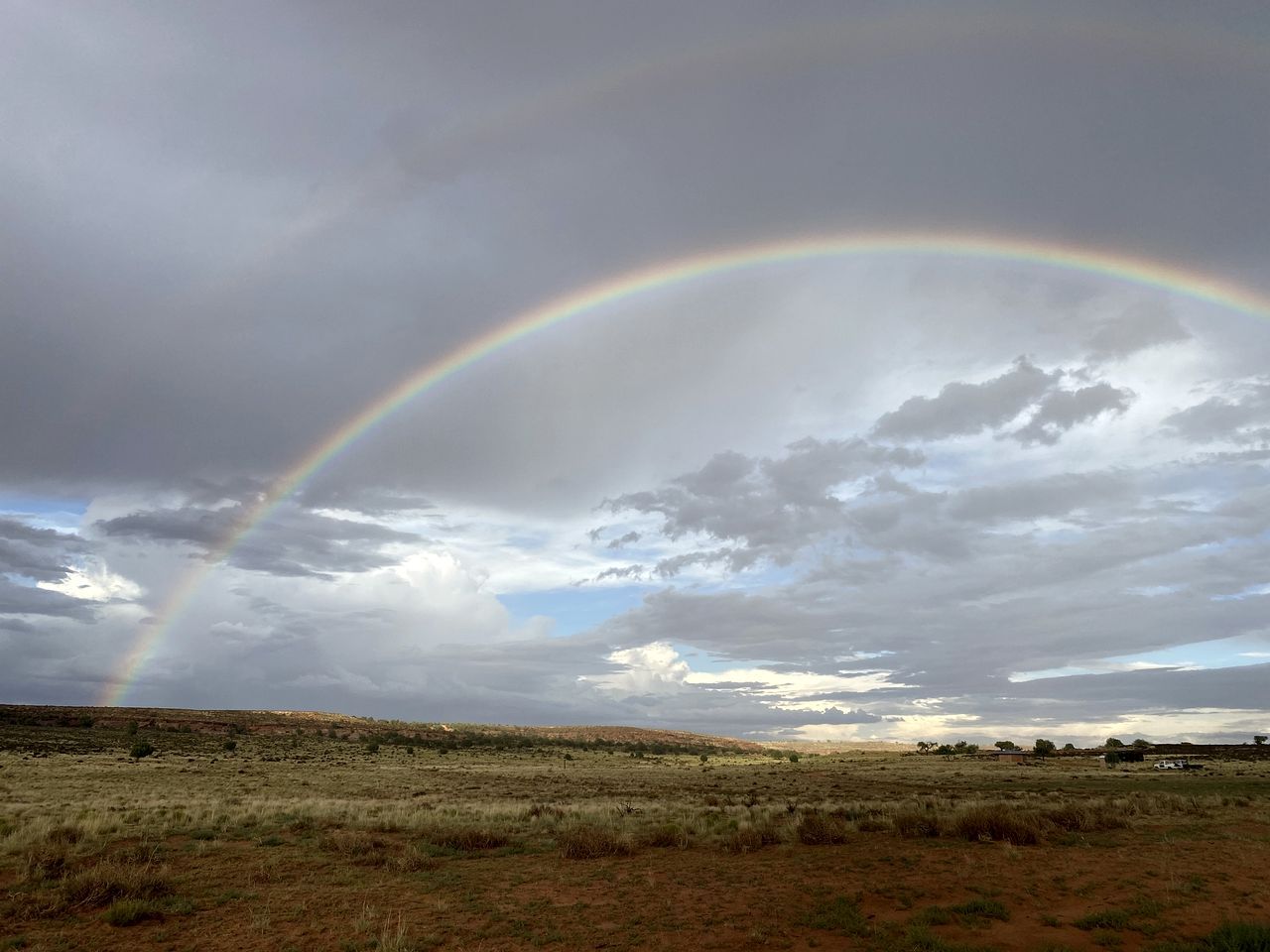 Un paisaje con un arcoíris que se extiende sobre un cielo nublado.