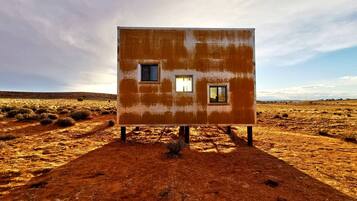 Edificio de una planta con dos ventanas, en un paisaje árido.
