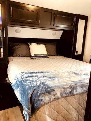 Una cama con cabecera acolchada, una almohada y una manta.