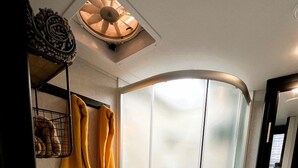 A modern bathroom with a curved shower enclosure, a toilet, and a sink with a mirror.