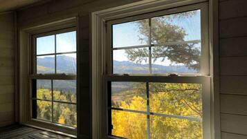 Two windows with a view of autumn foliage and distant mountains.