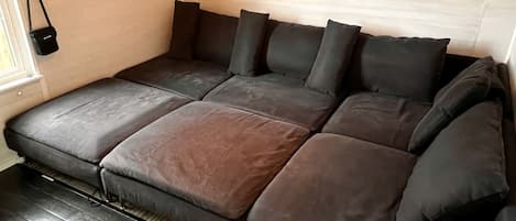 Un sofá cama con un reloj digital, un bolso pequeño y un estante con objetos.