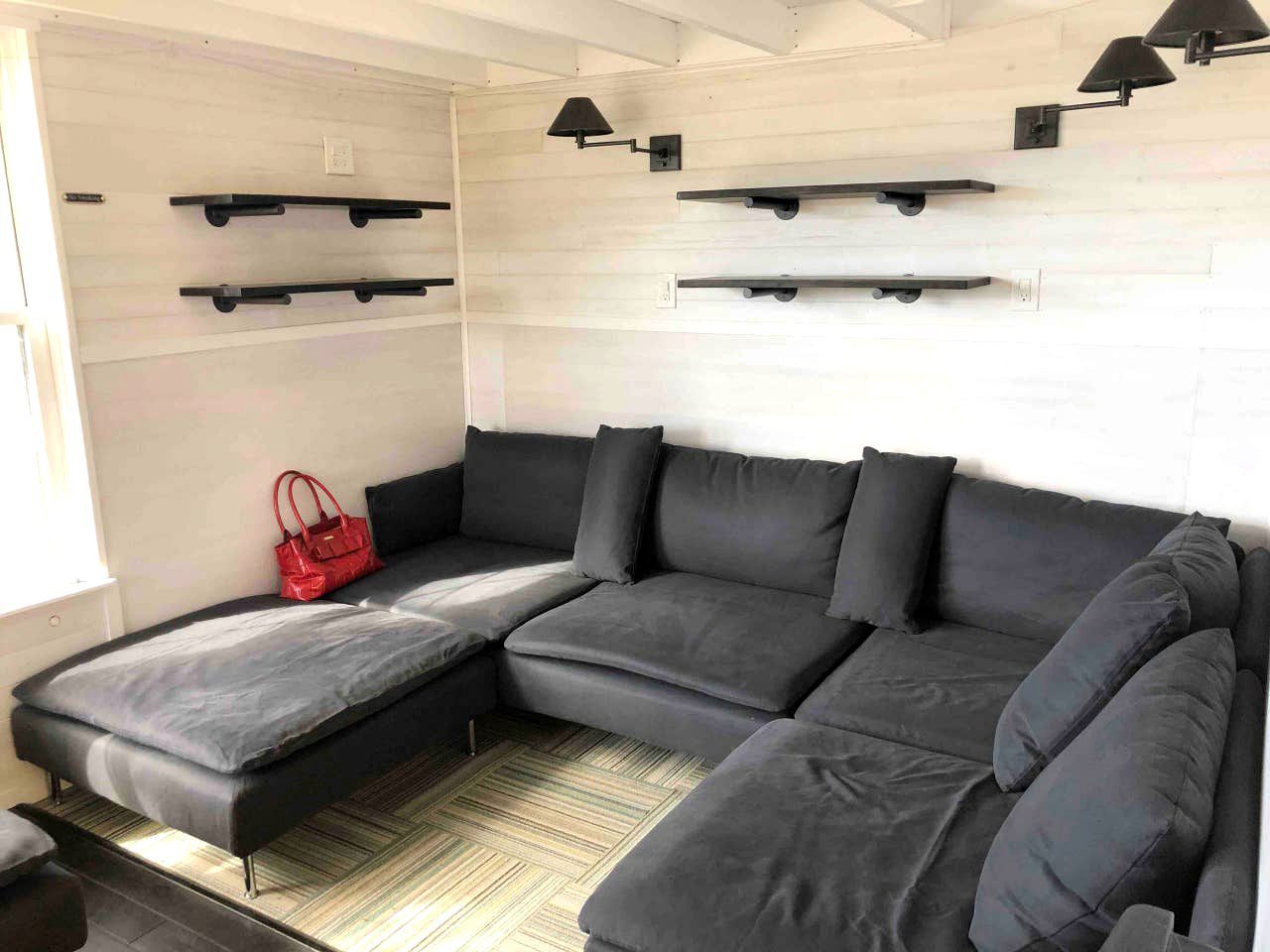 A modern living area with a sectional sofa, built-in shelves, and a red handbag on the floor.