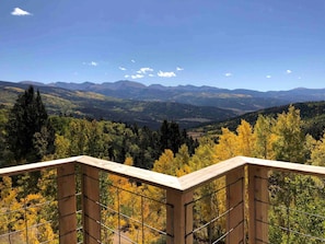A wooden balcony with a metal railing overlooking a mountainous landscape with autumn foliage. - Off-Grid yet Modern Tree House in the Sangre de Cristo Mountains, Colorado (Fort Garland)