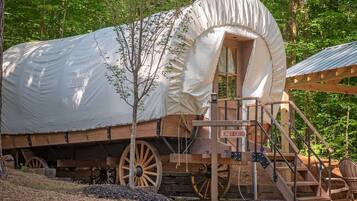 A covered wagon with a canopy, wooden steps, and a sign reading 'CANEY CREEK.'