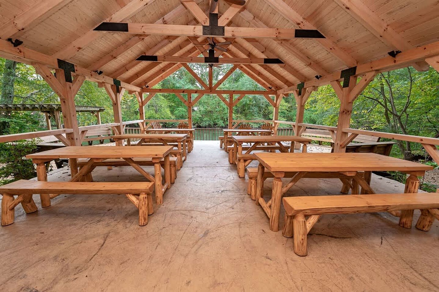 A covered wooden pavilion with picnic tables arranged in rows.