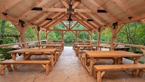 En överbyggd träpaviljong med picknickbord uppställda i rader.