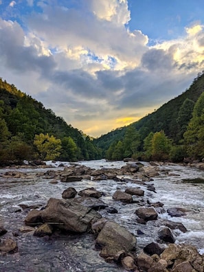 Un río con rocas, rodeado de colinas boscosas.
