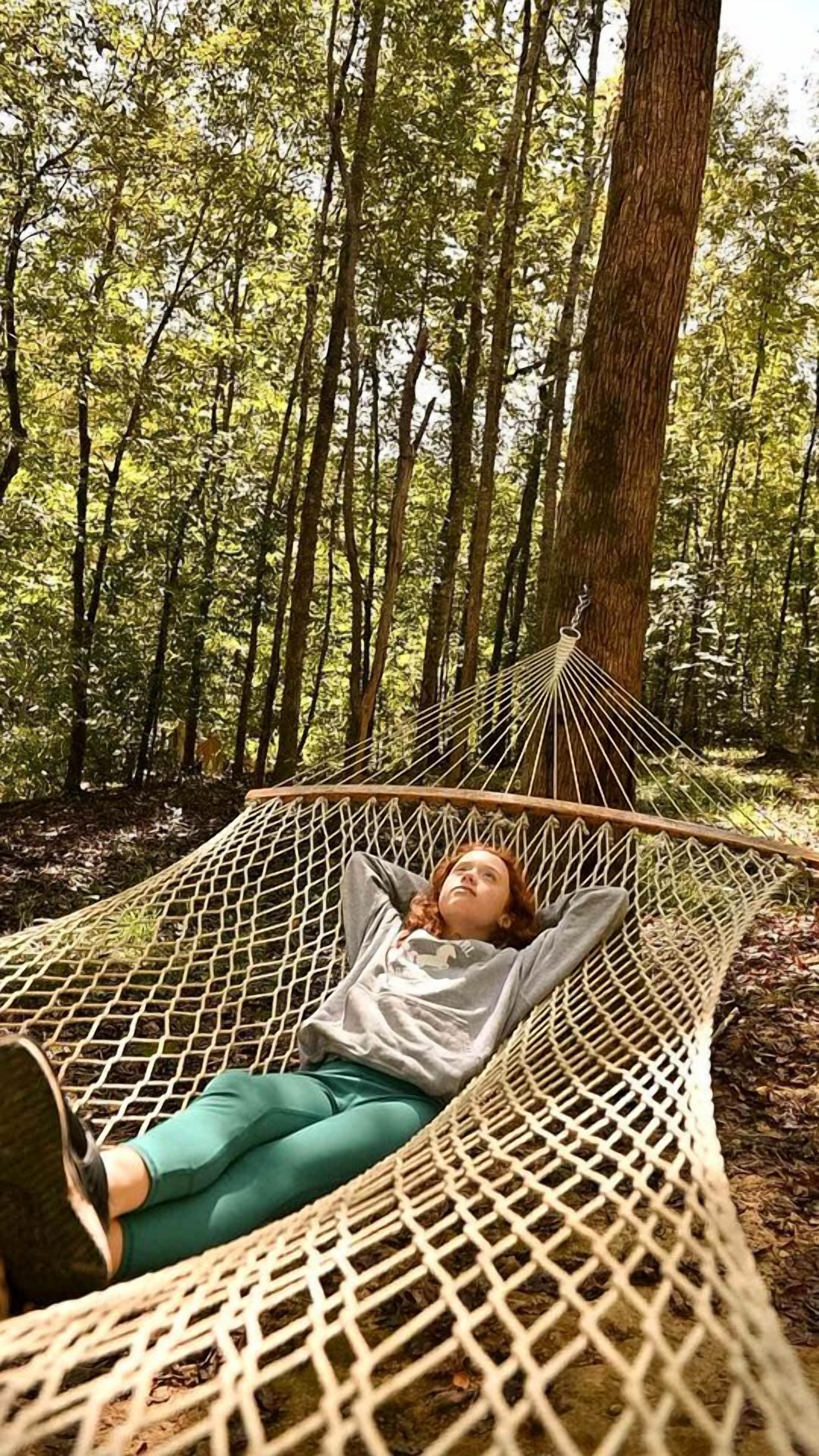 Eine Hängematte im Wald, darin liegt eine Person.