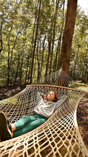 Eine Hängematte im Wald, darin liegt eine Person.