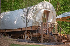 A covered wagon with a canopy, wooden steps, and a sign reading 'CANEY CREEK.'