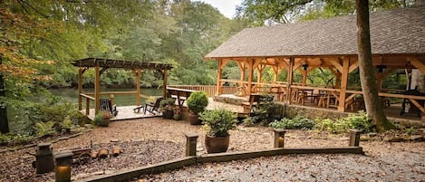 Un belvédère en bois, doté de bancs et de tables, entouré d’une zone recouverte de gravier et agrémentée de plantes en pot.