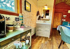 A rustic cabin interior with a kitchenette, a bed, and a bathroom.