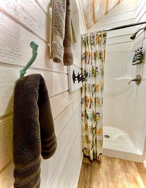 A bathroom with a shower, a towel rack, and a curtain with a floral pattern. - Delightful Dripping Springs Rental for a Tranquil Getaway in Texas (Dripping Springs)