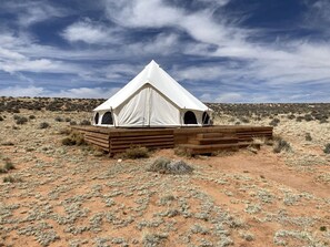 Una tenda con una piattaforma di legno, immersa in un paesaggio desertico.