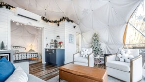 Ein gemütliches, helles Wohnzimmer mit Kamin, bequemen Sitzgelegenheiten und einem Weihnachtsbaum.