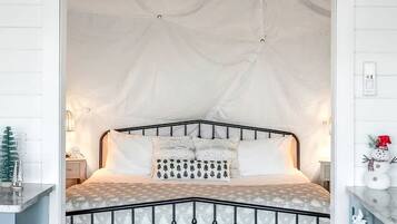 A bedroom with a curved bed, white walls, and a wooden floor.