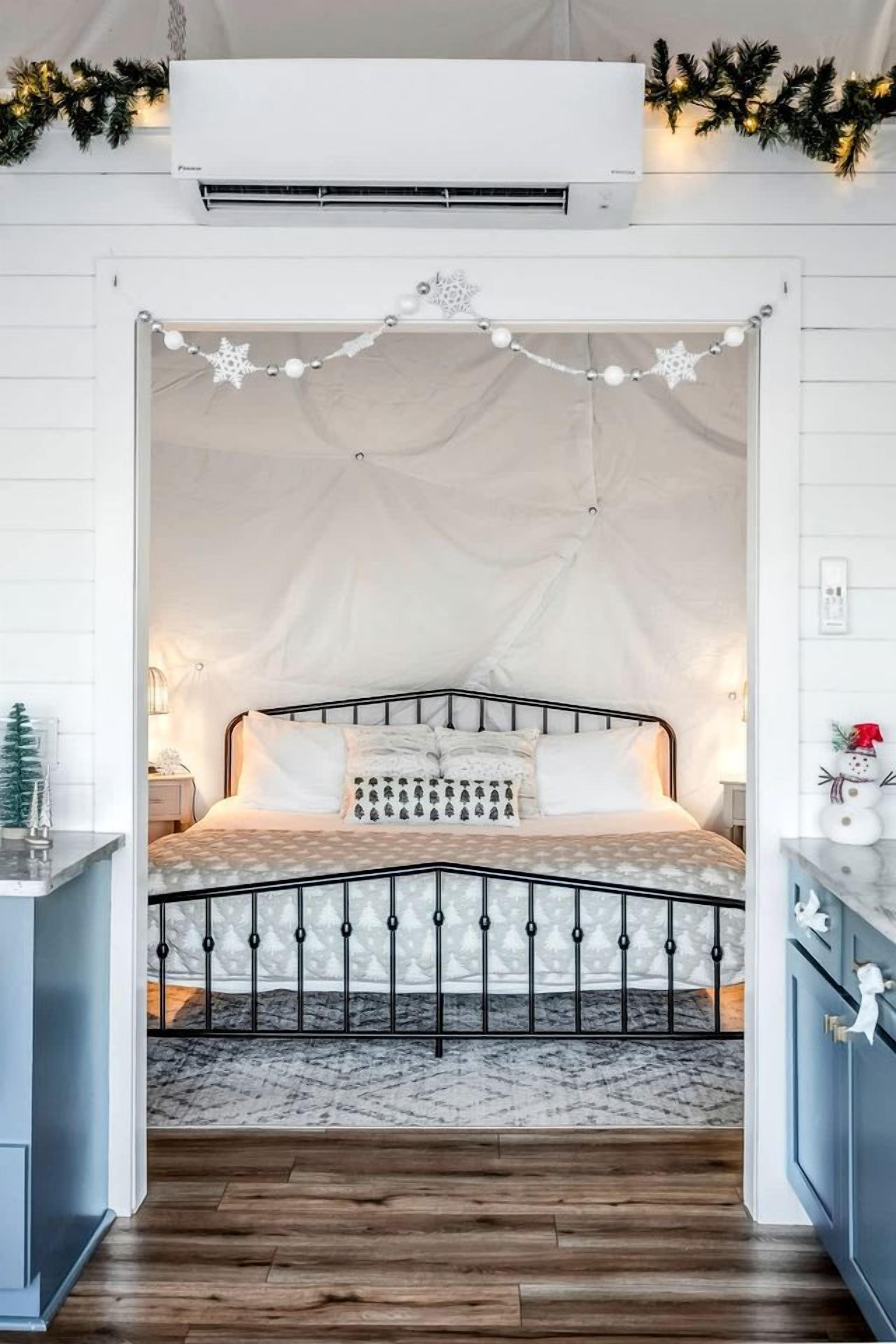 Ein Schlafzimmer mit einem bogenförmigen Bett, weißen Wänden und Holzboden.