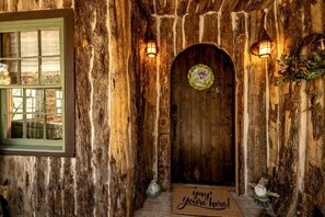 Una puerta de madera rústica con un vitral, una ventana con marco verde y un felpudo.