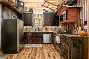 Una cocina rústica con armarios de madera, un refrigerador de acero inoxidable, una encimera de madera y una ventana con vistas.