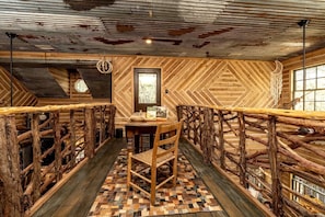 Een rustieke houten kamer met een visgraatmotief muur, een houten tafel met stoelen en een raam met uitzicht.