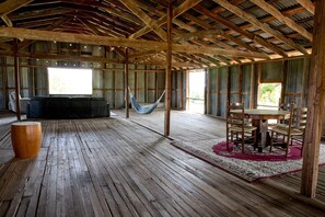 A rustic wooden interior with a hammock, a round wooden table, and a sofa. - Magical Treehouse with Slide by Brazos River for Family Glamping Adventures in Texas (Weatherford)