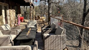 Een terras buiten met wicker meubels, een eettafel en een rode tafelkleed.