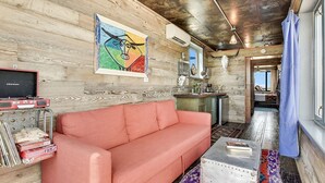 A cozy living area with a red sofa, a colorful abstract painting, and a rustic wooden wall.