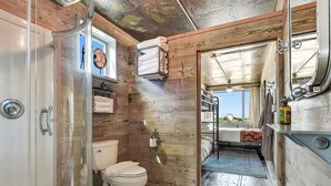 A bathroom with a glass shower enclosure, a toilet, and a sink.