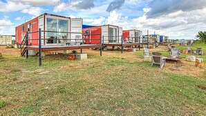 Une série de conteneurs maritimes disposés de manière à créer un espace de détente extérieur rustique, avec des tables et des chaises en métal.