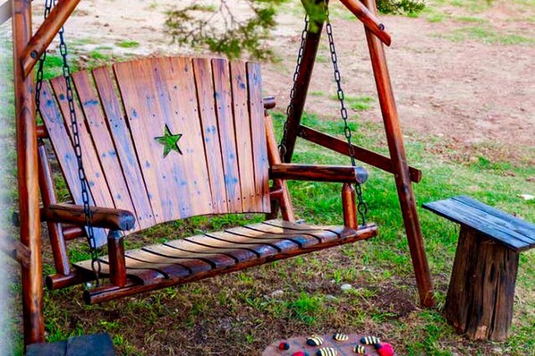 A wooden swing with a star decoration, a bench, and a small table.