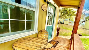 A wooden deck with a table and chairs, a door with a sign, and a window.