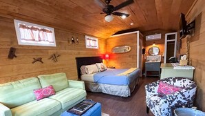 A cozy room with a sofa, a bed, a chair, and a small table.