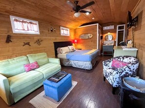 Ein gemütliches Zimmer mit Sofa, Bett, Sessel und kleinem Tisch.