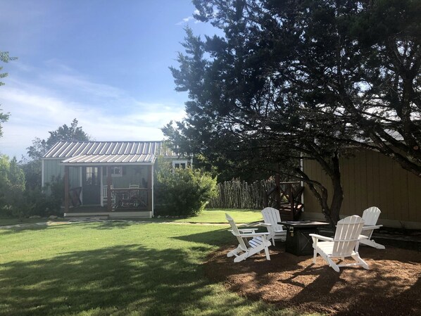 A house with a covered porch, a lawn, and two white Adirondack chairs.
