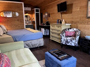 A cozy room with a bed, a chair, a dresser, and a television.