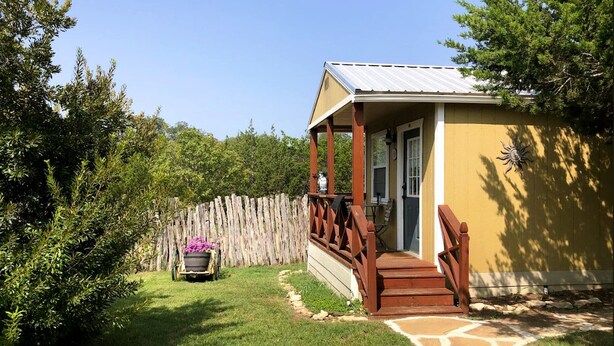 A house with a porch, a wooden fence, and a garden.
