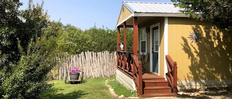 Une maison avec un porche, une clôture en bois et un jardin.