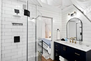 A modern bathroom with a large mirror, dark cabinets, and a glass shower enclosure. - Fully-Equipped Lake Dome with Beautiful Interior and Exterior in Tennessee (Smithville)