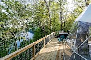 A deck with a view of a lake, surrounded by trees.
