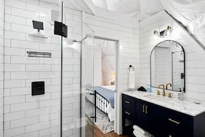 A modern bathroom with a large mirror, dark cabinets, and a glass shower enclosure. - Fully-Equipped Lake Dome with Beautiful Interior and Exterior in Tennessee (Smithville)