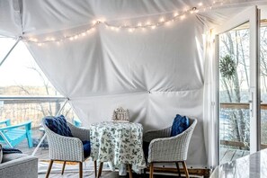 A covered outdoor seating area with a table and chairs, string lights, and a view of the outdoors. - Fully-Equipped Lake Dome with Beautiful Interior and Exterior in Tennessee (Smithville)