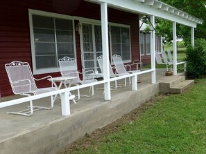 A covered porch with white metal chairs and a concrete floor. - Spacious Cottage Rental for Group Getaway on Ranch near Dallas, Texas (Weatherford)