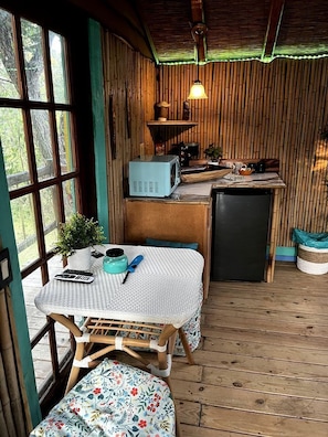 Una cocina rústica con microondas, refrigerador y paredes de madera.