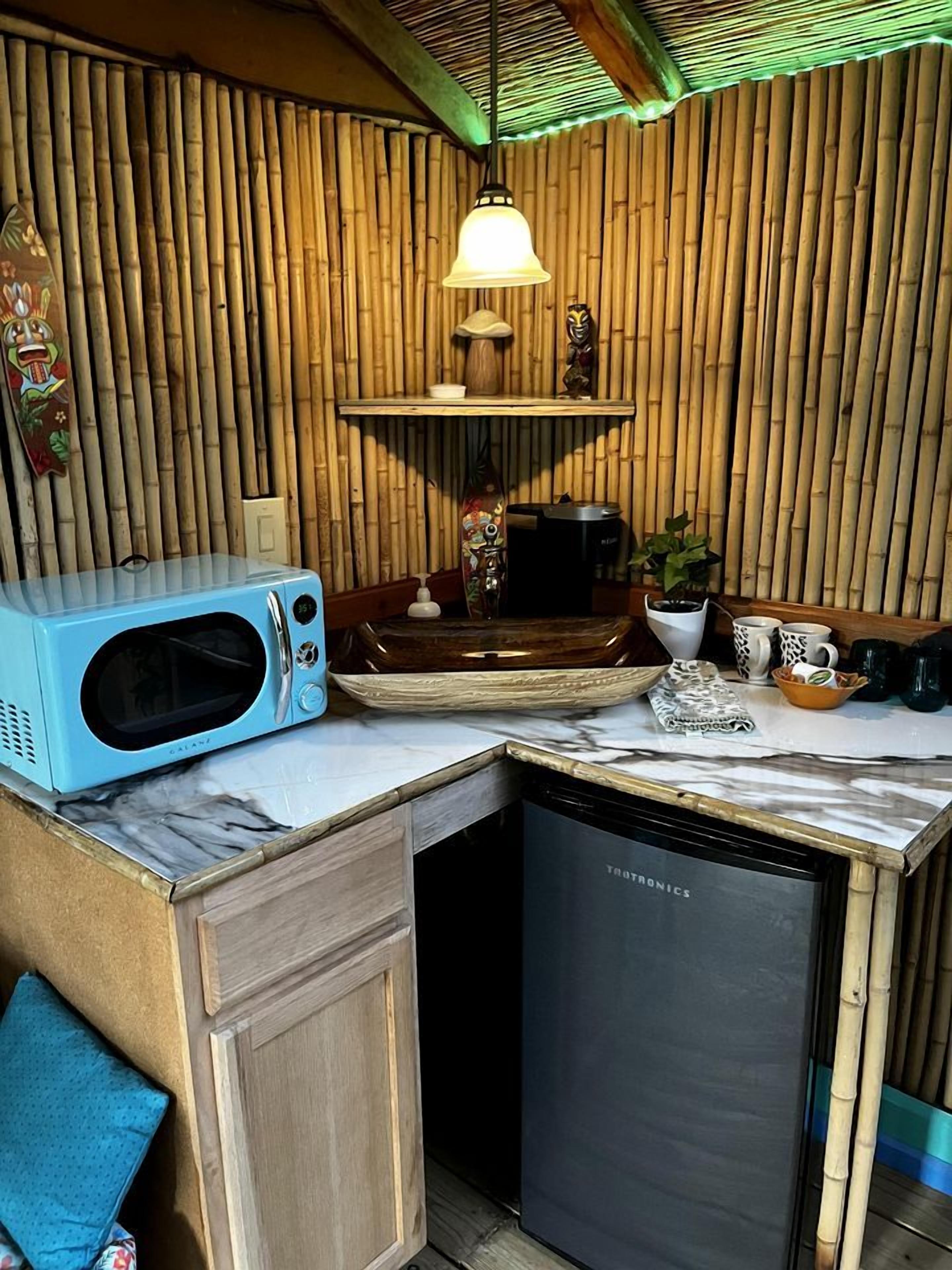 Een kleine keuken met een magnetron, koffiezetapparaat en vaatwasser.