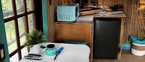 A rustic kitchen with a microwave, refrigerator, and wooden walls.