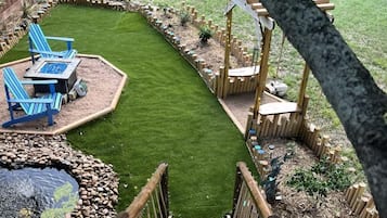 Un patio trasero con una terraza de madera, un pequeño estanque y una zona cubierta de césped.