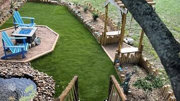 A backyard with a wooden deck, a small pond, and a grassy area.