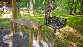 Un banco de madera y una parrilla de barbacoa en una zona boscosa.
