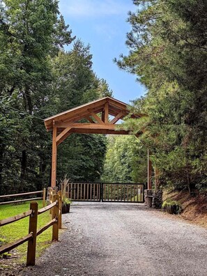 Una entrada con pérgola de madera y un sendero de grava que la atraviesa.